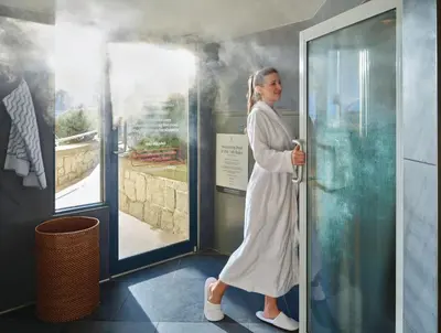 a woman in a white robe walking through a door at Pan Pacific Whistler Mountainside in Whistler