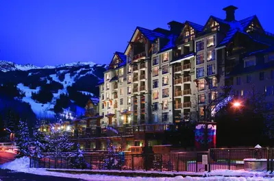 a large building in the snow at night at Pan Pacific Whistler Village Centre in Whistler