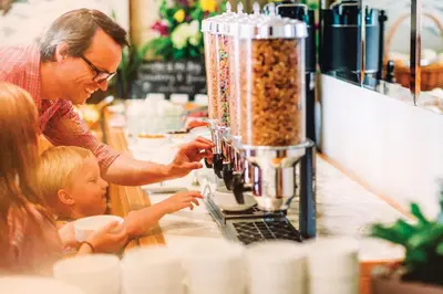 a man and a child sitting at a counter with a blender at Pan Pacific Whistler Village Centre in Whistler