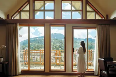 a woman in a white dress looking out of a window at Pan Pacific Whistler Village Centre in Whistler