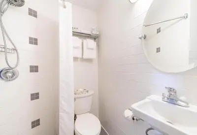 a white bathroom with a toilet and a sink at Executive Inn Whistler in Whistler