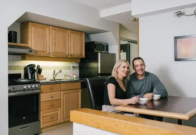 a man and woman sitting at a table in a kitchen at Executive Inn Whistler in Whistler