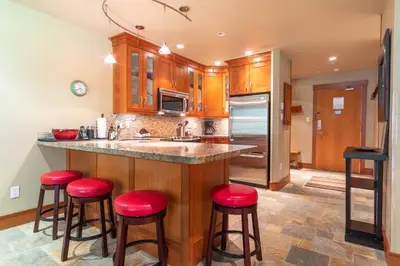 a kitchen with wooden cabinets and red bar stools at Wildwood Lodge by Outpost Whistler in Whistler