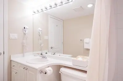 a white bathroom with a sink and a mirror at Deer Lodge by Outpost Whistler in Whistler