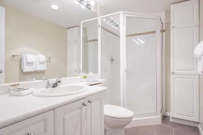 a white bathroom with a sink and a shower at Deer Lodge by Outpost Whistler in Whistler