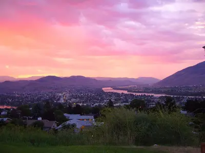 a view of a city and a river at sunset at Hospitality Inn in Kamloops