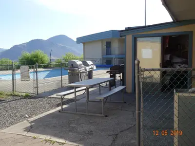 a picnic table in front of a fence with a grill at Hospitality Inn in Kamloops