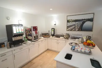 a kitchen with white cabinets and a counter with fruit on it at Robin Hood Inn and Suites in Victoria