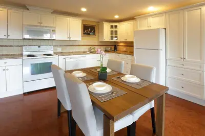 a kitchen with a wooden table and white appliances at Lovely J Home -Stunning river view cozy two bedroom private suite in New Westminster