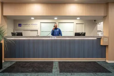 a man standing behind a counter in a lobby at Campus Tower Suite Hotel in Edmonton