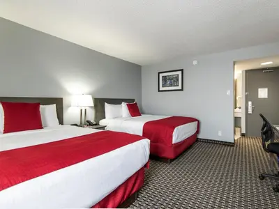 a hotel room with two beds with red sheets at Paradise Inn & Conference Centre in Grande Prairie