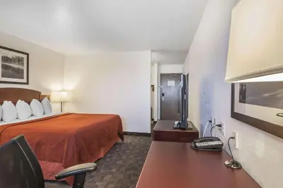 a hotel room with a bed and a desk with a phone at Quality Hotel & Conference Centre in Fort McMurray