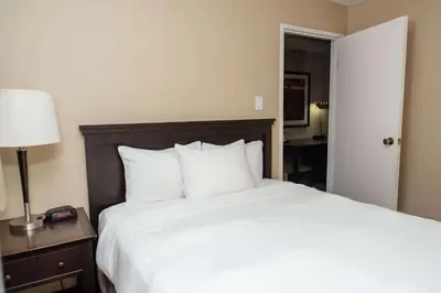 a bedroom with a large white bed and a lamp at Baymont by Wyndham Red Deer in Red Deer