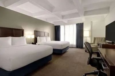 a hotel room with two beds and a desk at Wyndham Edmonton Hotel and Conference Centre in Edmonton