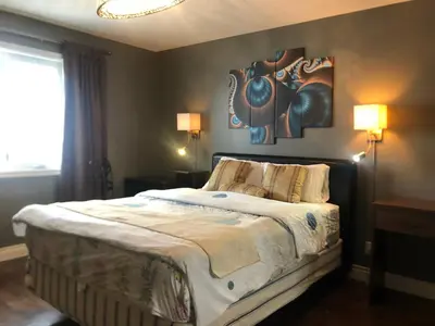 a bedroom with a bed with two lamps and a painting on the wall at Citadel hill cr community! in Calgary