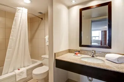 a bathroom with a sink and a toilet and a mirror at Edmonton Inn and Conference Centre in Edmonton