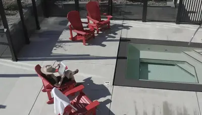 a woman sitting in red chairs next to a swimming pool at Spring Creek Penthouse by Canadian Rockies Vacation Rentals in Canmore