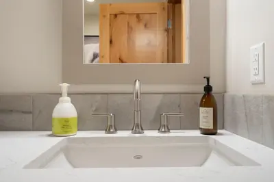 a bathroom sink with a bottle of soap and a mirror at Spring Creek Penthouse by Canadian Rockies Vacation Rentals in Canmore