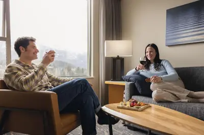 a man and woman sitting on a couch in a hotel room at The Westin Resort & Spa, Whistler in Whistler