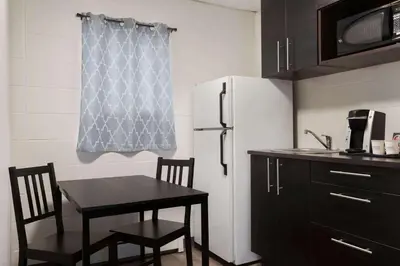 a small kitchen with a table and a refrigerator at Howard Johnson by Wyndham Grande Prairie in Grande Prairie