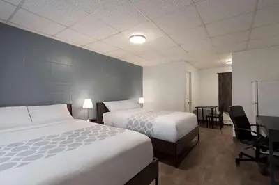 a hotel room with two beds and a desk at Howard Johnson by Wyndham Grande Prairie in Grande Prairie