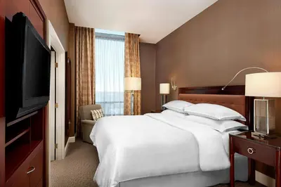 a hotel room with a large bed and a flat screen tv at Sheraton Suites Calgary Eau Claire in Calgary