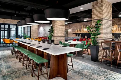 a dining room with a long table and green chairs at Sheraton Suites Calgary Eau Claire in Calgary