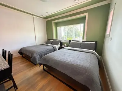 two beds in a room with a window at Victory House in Burnaby