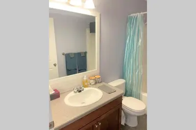 a bathroom with a sink and a toilet and a mirror at Spacious Duplex in Camrose