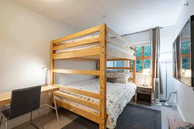 a bedroom with a bunk bed and a desk with a chair at Updated Townhouse in Village. Pool/Hot Tub/Parking in Whistler