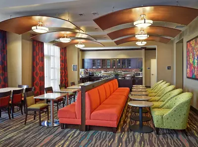 a restaurant with orange couches and tables and a bar at Homewood Suites Calgary Airport in Calgary
