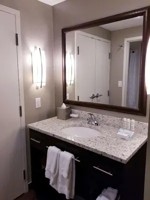 a bathroom with a sink and a large mirror at Homewood Suites Calgary Airport in Calgary