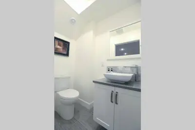 a white bathroom with a toilet and a sink at Vancouver Traveller Cottage in Vancouver