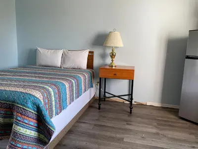 a bedroom with a bed and a table with a lamp at Y-5 Motel in Barrière