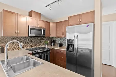 a kitchen with wooden cabinets and a stainless steel refrigerator at GlobalStay Downtown Calgary Condos in Calgary