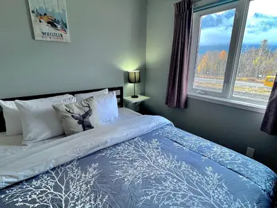 a bed with a blue and white comforter and a window at Canadian Rockies Chalets by Trilink - 2 & 3 Bedroom Condos - Self Check-In - Walking Distance to Downtown - Free Parking - Pet-Friendly - No AC in Canmore