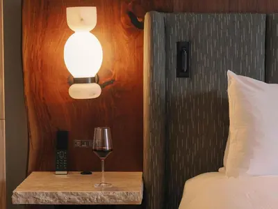 a glass of wine on a table next to a bed at Rimrock Banff, Emblems Collection in Banff