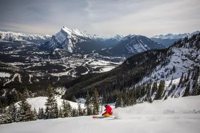 a person is skiing down a snow covered mountain at Banff Park Lodge in Banff