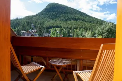 a balcony with two chairs and a view of a mountain at Fox Hotel and Suites in Banff