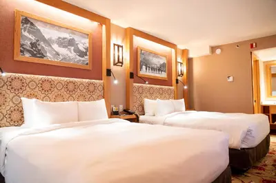 two beds in a hotel room with white sheets at Banff Ptarmigan Inn in Banff