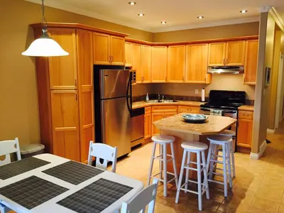 a kitchen with a refrigerator and a table with stools at Grandma's Elephant Hideaway in Penticton