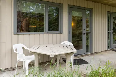 a wooden table and two white chairs outside of a house at Tunnel Mountain Resort in Banff
