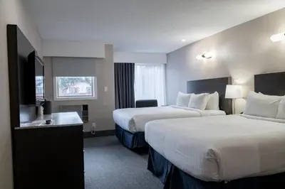 a hotel room with two beds and a window at Red Carpet Inn in Banff