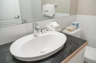 a white bathroom with a sink and a toilet at Red Carpet Inn in Banff
