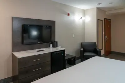 a hotel room with a bed and a tv and a chair at Red Carpet Inn in Banff