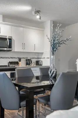 a kitchen with a table with chairs and a vase of flowers at Modern House with Private Backyard & Fireplace in Calgary