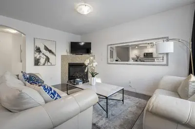 a living room with white furniture and a fireplace at Modern House with Private Backyard & Fireplace in Calgary