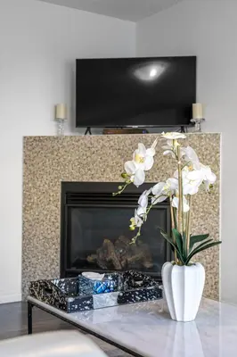 a vase of flowers on a table in front of a fireplace at Modern House with Private Backyard & Fireplace in Calgary