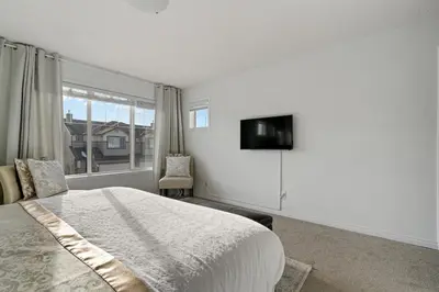 a bedroom with a bed and a tv on a wall at Modern House with Private Backyard & Fireplace in Calgary