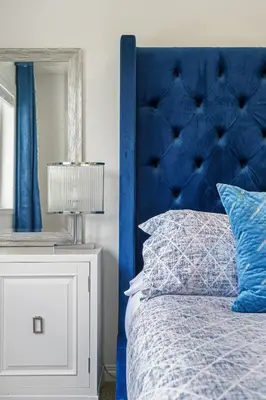 a bed with a blue headboard and a white night stand at Modern House with Private Backyard & Fireplace in Calgary